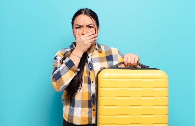 Hispanische Frau, die Mund mit Händen mit einem schockierten, überraschten Ausdruck bedeckt, ein Geheimnis hält oder oops sagt