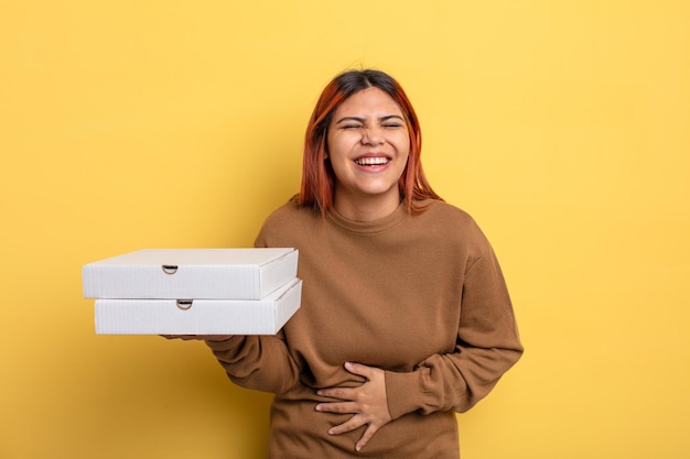 Hispanische Frau lacht laut über einen lustigen Witz zum Mitnehmen von Pizzen