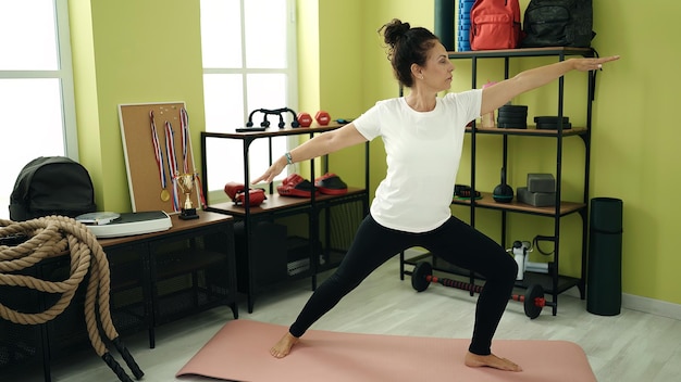 Hispanische Frau mittleren Alters trainiert Yoga im Sportzentrum