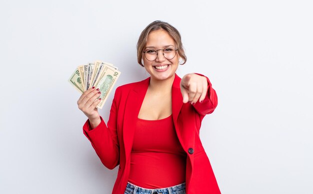 Hispanische hübsche Frau, die auf die Kamera zeigt und Ihr Geschäfts- und Banknotenkonzept auswählt