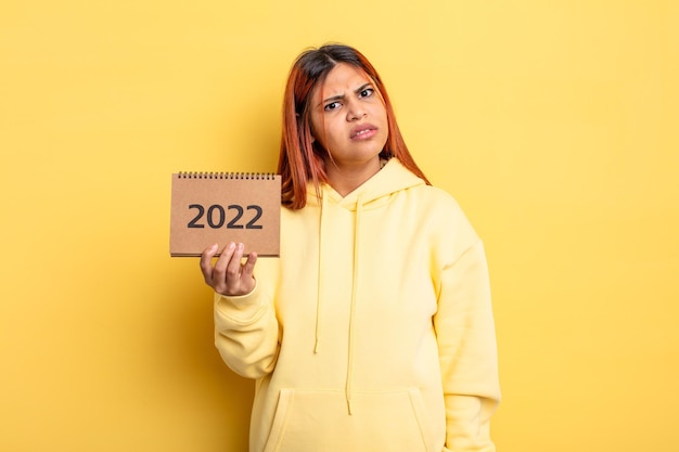 Hispanische hübsche Frau, die einen Kalender oder eine Tagesordnung 2022 hält