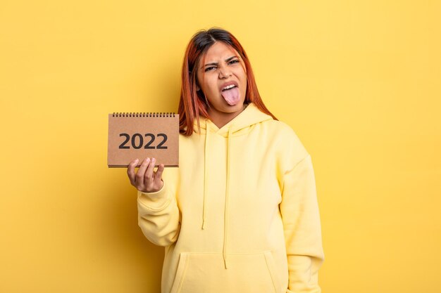 Hispanische hübsche Frau, die einen Kalender oder eine Tagesordnung 2022 hält