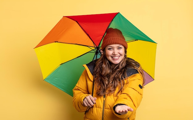 Hispanische hübsche frau, die glücklich mit freundlichem lächeln lächelt und ein konzept anbietet und zeigt. regenschirmkonzept