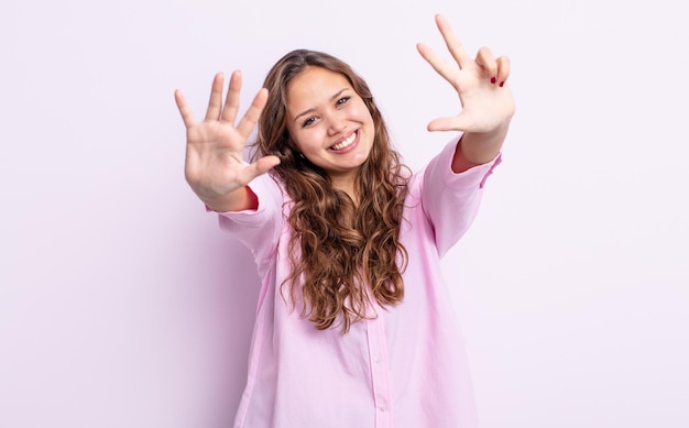 Hispanische hübsche Frau, die lächelt und freundlich aussieht, die Nummer acht oder acht mit der Hand nach vorne zeigt und herunterzählt