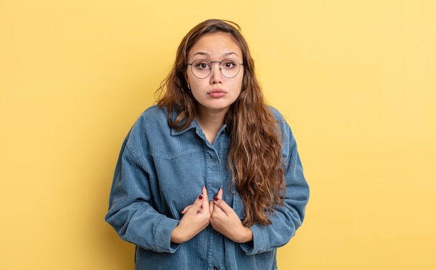 Hispanische hübsche Frau, die mit einem verwirrten und fragenden Blick auf sich selbst zeigt, schockiert und überrascht, ausgewählt zu werden