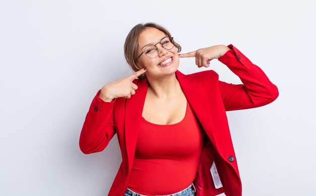 Hispanische hübsche Frau, die selbstbewusst lächelt und auf ein breites Lächeln zeigt. Geschäftsfrau