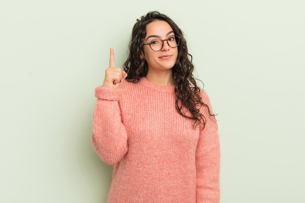 Hispanische hübsche Frau, die sich wie ein Genie fühlt, das stolz den Finger in die Luft hält, nachdem sie eine großartige Idee mit dem Spruch Eureka verwirklicht hat