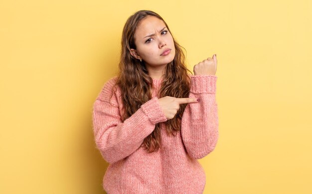 Hispanische hübsche Frau, die ungeduldig und wütend aussieht, auf die Uhr zeigt, um Pünktlichkeit bittet, will pünktlich sein