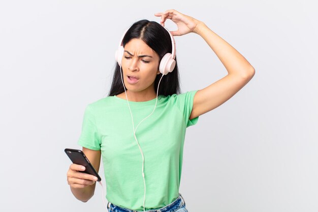 Hispanische hübsche Frau mit Kopfhörern und einem Smarphone