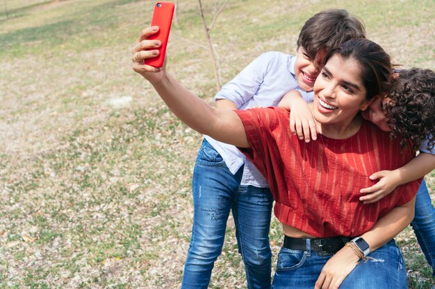 Hispanische Mutter mit ihren Kindern macht ein Selfie mit ihrem Handy im Park