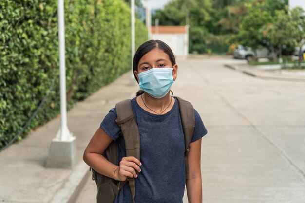Hispanische Schülerin, die sich auf die Schule fertig macht, Mädchen mit Schutzmaske, das das Haus verlässt
