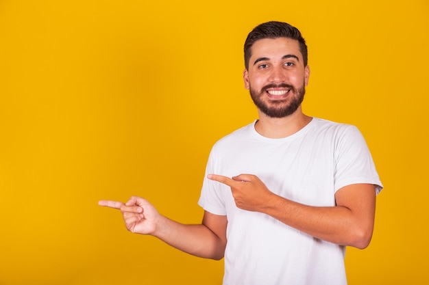 Hispanischer Brasilianer mit Armen, Händen und Fingern zeigten zur Seite für negativen Raum Werbekonzept Vorschlag Konzept Auswahl Konzept gelber Hintergrund