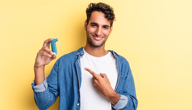 Hispanischer gutaussehender Mann, der fröhlich lächelt, sich glücklich fühlt und auf die Seite zeigt. Asthma-Konzept