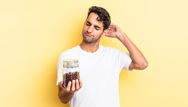 Hispanischer gutaussehender Mann, der glücklich lächelt und träumt oder zweifelt. Kaffeebohnen Flasche