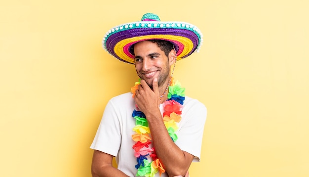 Hispanischer gutaussehender Mann, der mit einem glücklichen, selbstbewussten Ausdruck mit der Hand am Kinn lächelt. mexikanisches partykonzept