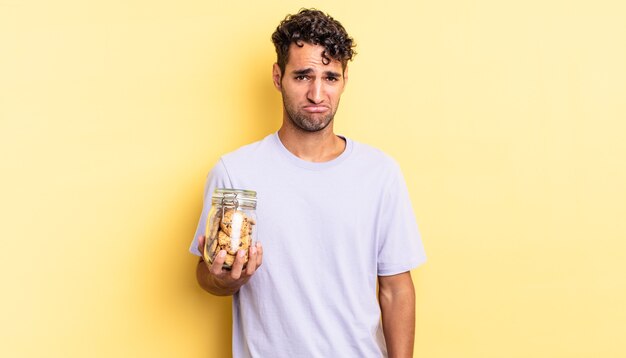 Hispanischer gutaussehender Mann, der sich traurig und weinerlich mit einem unglücklichen Blick und Weinen fühlt. Cookies-Konzept