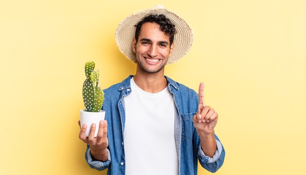 Hispanischer gutaussehender Mann, der stolz und selbstbewusst lächelt und das Konzept für Landwirte und Kakteen Nummer eins macht