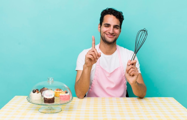 Hispanischer, gutaussehender Mann, der stolz und selbstbewusst lächelt und hausgemachte Kuchen zubereitet