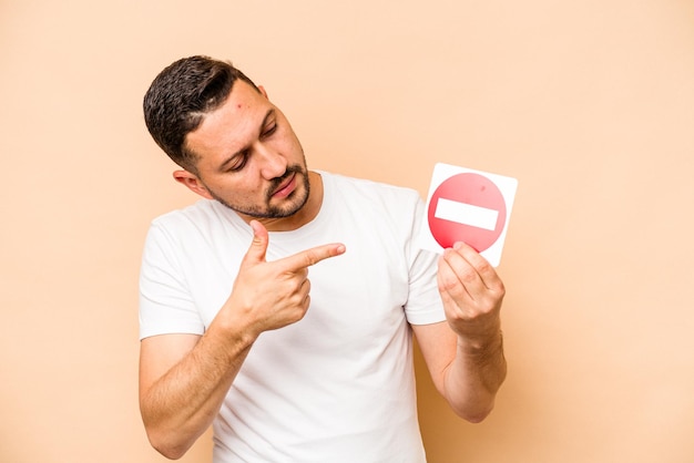 Hispanischer kaukasischer Mann mit einem verbotenen Schild isoliert auf beigem Hintergrund