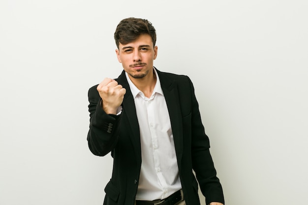 Hispanischer Mann des jungen Geschäfts, der Faust zur Kamera, aggressiver Gesichtsausdruck zeigt.