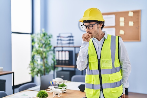 Hispanischer Mann mit Architektenhelm fühlt sich unwohl und hustet als Symptom für Erkältung oder Bronchitis. Gesundheitskonzept.