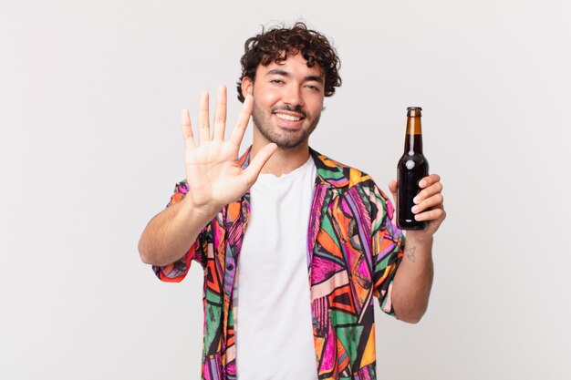 Hispanischer Mann mit Bier lächelnd und freundlich aussehend, Nummer fünf oder fünft mit der Hand nach vorne zeigend, herunterzählen