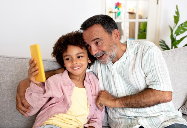 Hispanischer Opa und Enkel telefonieren gemeinsam zu Hause