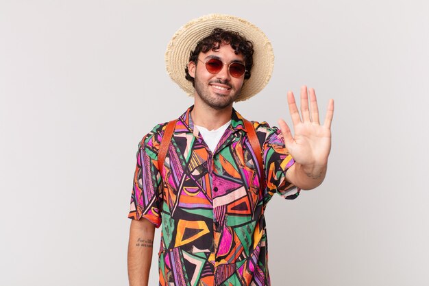 Hispanischer Touristenmann, der glücklich und fröhlich lächelt, die Hand winkt, Sie begrüßt und begrüßt oder sich verabschiedet
