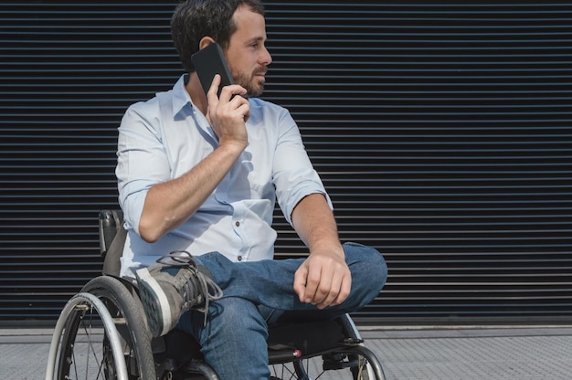 Hispano latino adulto hombre de negocios caucásico, ejecutivo con ropa informal, con barba en silla de ruedas hablando por teléfono, mirando hacia un lado, con espacio para copiar.