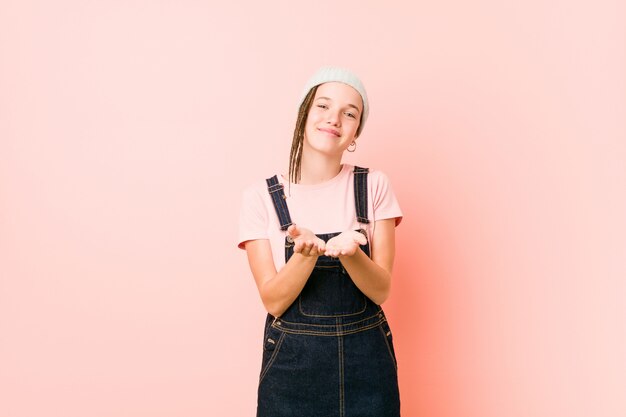 Hispter mujer adolescente sosteniendo algo con las palmas, ofreciendo.