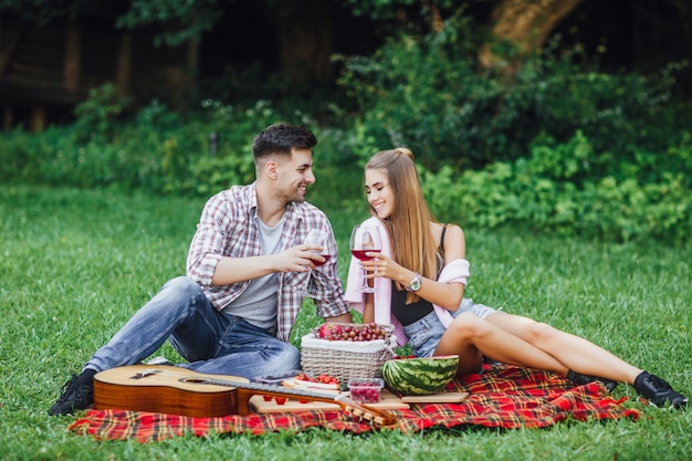 Historia de amor Hermosa pareja disfrutando de un picnic al aire libre, están sentados en una alfombra