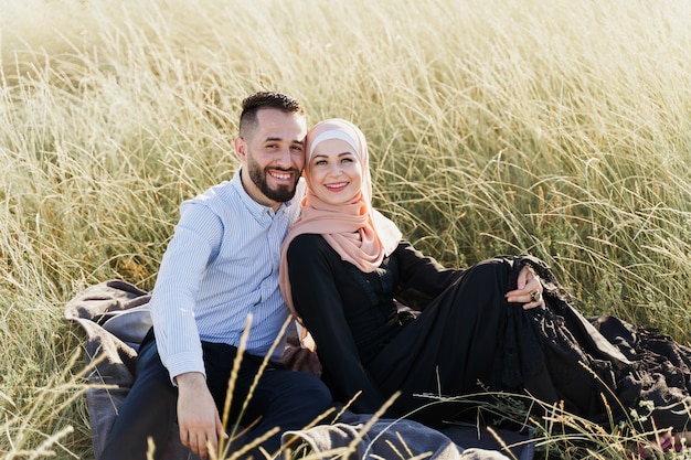 Historia de amor musulmana. Asientos de pareja mixta en el césped, sonrisas y abrazos