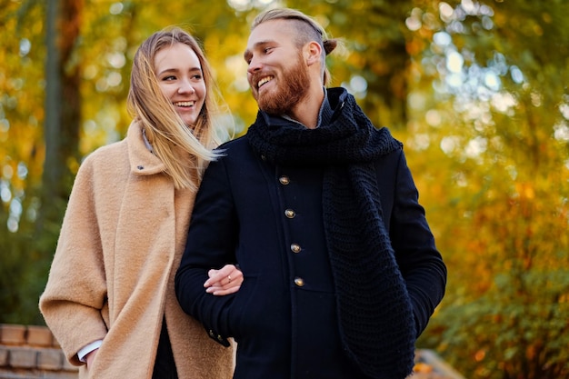 Historia de amor de otoño. El hombre barbudo pelirrojo abraza a la linda mujer rubia en la cita en un parque de otoño.