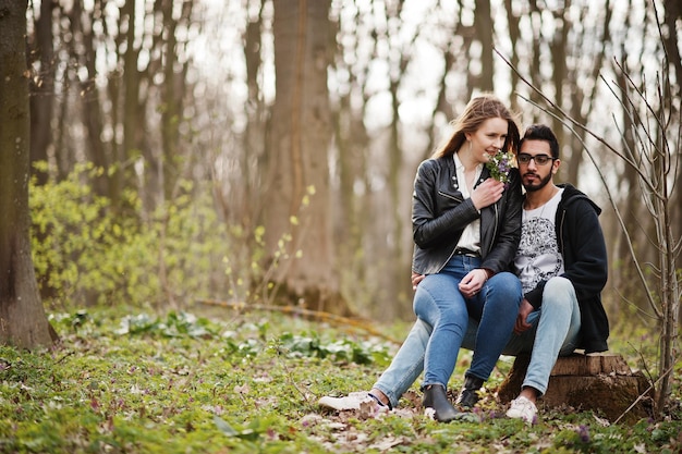 Historia de amor de una pareja multirracial genial en el bosque de primavera Están sentados en un tocón