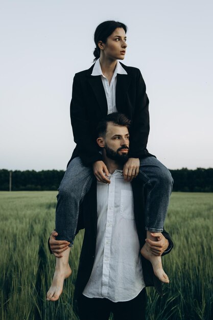 Historia de amor Retrato de una joven pareja amorosa caucásica abrazándose mientras está de pie en un campo verde y posando para la foto