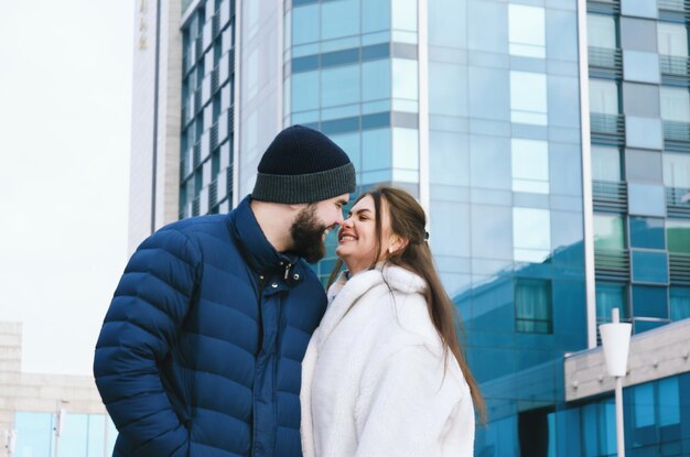 História de amor de casal andando na cidade de inverno nevado. Jovem de casaco azul com barba. mulher bonita