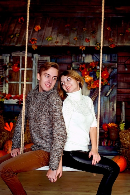 História de amor de um jovem casal feliz e engraçado em estúdio, casa aconchegante. Decorações de outono, abóboras laranja.