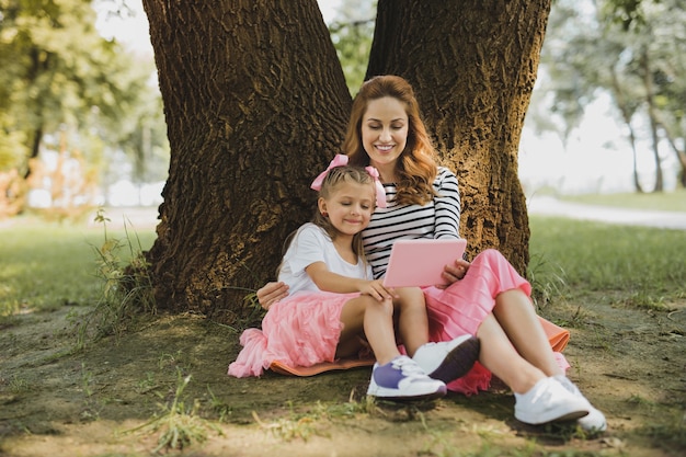 Historieta divertida. Madre e hija viendo divertidos dibujos animados en su computadora portátil pasar tiempo al aire libre