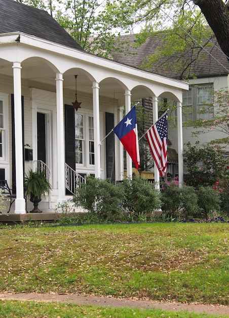 Historisches Haus mit Texas und amerikanischen Fahnen Frühling