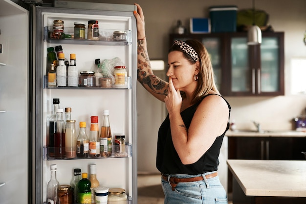 Hmm, qué hacer para la cena Foto de una mujer joven que busca dentro de un refrigerador en casa