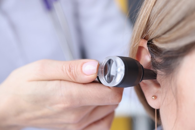 HNO-Arzt, der das Ohr des Patienten mit einer Otoskop-Nahaufnahme betrachtet.