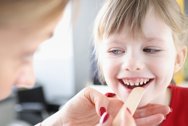 HNO-Arzt, der den Hals eines kleinen Kindes mit einem Spatel untersucht. Diagnose und Behandlung von Mandelentzündung bei Kindern Konzept