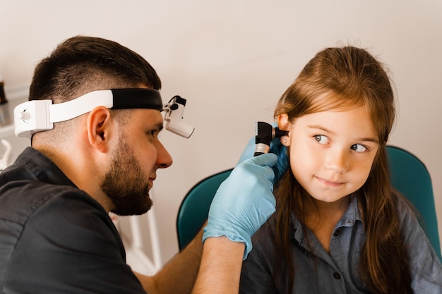 HNO-Arzt mit Otoskop Otoskopie Kinderarzt HNO-Arzt sieht durch Otoskop die Ohren des Kindes Otoskopie Behandlung Ohrenschmerzen