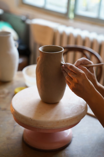 Hobby de alfarería manos de ceramista profesional trabajan en jarrón de alfarero en estudio crean jarra de arcilla cruda