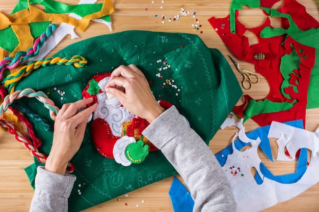 Foto hobby, artesanato, criatividade, conceito de tempo livre em casa. mãos femininas fazendo decoração de natal. apliques de feltro, agulhas de feriado. camada plana, vista superior