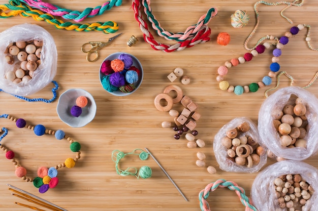 Hobby, Basteln, Kreativität, Freizeit zu Hause Konzept. Stricken, Häkeln, umweltfreundliche Baumwolle und bunte Babyperlen aus Holz, Beißringe für Neugeborene. Flache Lage, Ansicht von oben