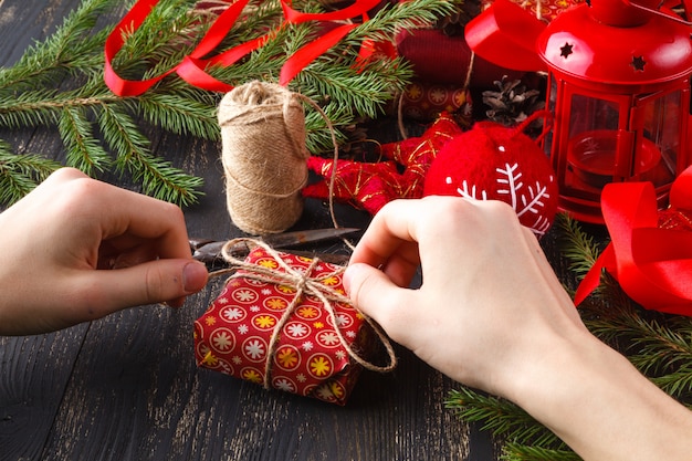 Hobby creativo manos envuelven regalo de navidad hecho a mano en papel artesanal con cinta de hilo