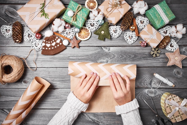 Hobby creativo Regalos de Navidad con herramientas y decoraciones. Embalaje presenta en mesa de madera, vista superior.