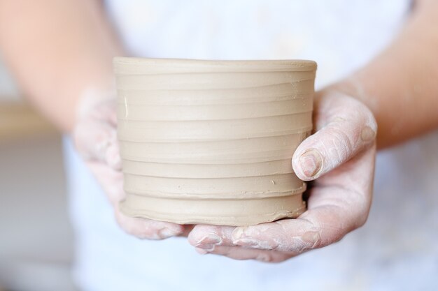 Hobby de artesanato em cerâmica. mãos mostrando uma panela de barro recém-feita