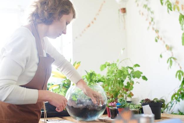 Hobby. Una mujer crea un mini terrario con plantas para el diseño de interiores.